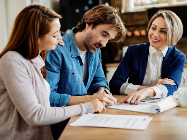 Happy financial advisor having consultations with young couple at their home